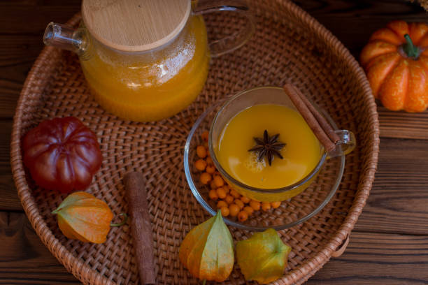 istock yellow tea with sea buckthorn berries in a glass teapot. Decorated with physalis and autumn pumpkins, dried herbs for winter in the background 1663247607