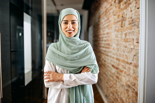 Young beautiful businesswoman wearing hijab posing for a shot at modern office hallway