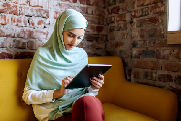 istock Young beautiful businesswoman  wearing hijab using digital tablet while sitting on a sofa at modern office 1663250260