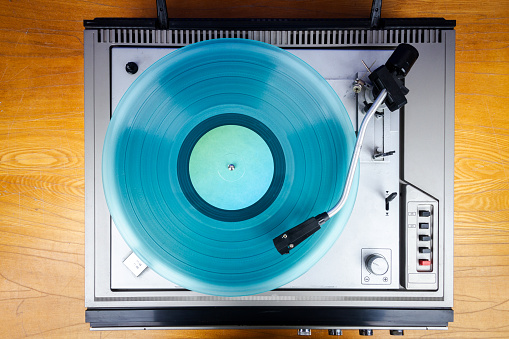 Vintage turntable vinyl record player with turquoise vinyl on a table