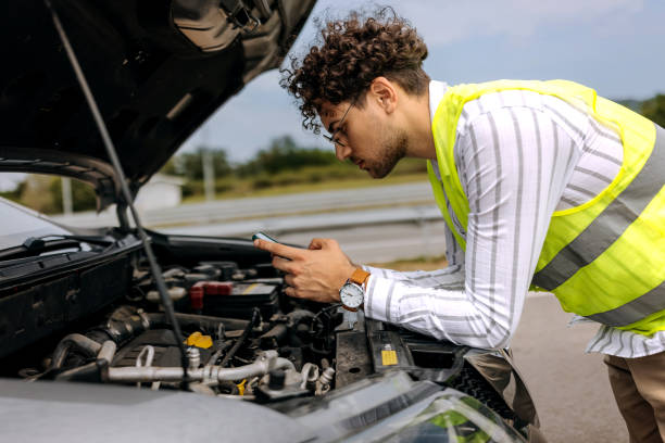 istock Young man with reflective west text messaging for help for his broken vehicle on highway 1663259386
