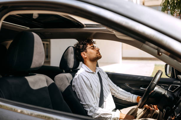 Tired young well dressed man sitting in car stock photo