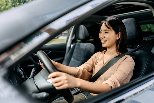 Young beautiful smiling Japanese woman driving car