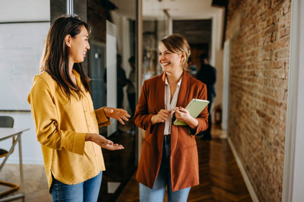 istock Two female colleagues talking in a hallway of modern office 1663267964