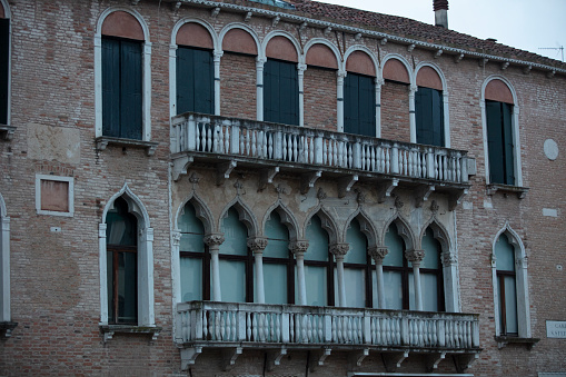 Window in a old weathered brownstone wall in the center of the old Italian city Venice