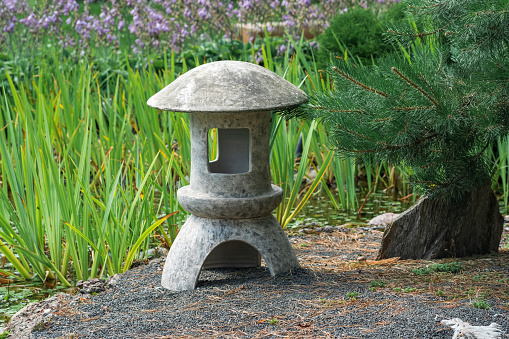 stone lantern on a small island in the middle of a pond in a Japanese garden