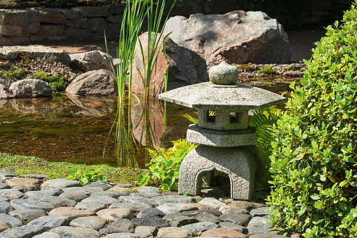 stone lantern on the bank of a pond in a Japanese garden