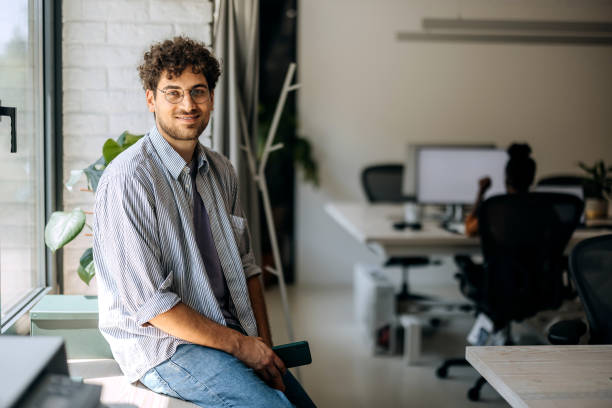 istock Young casually clothed man posing for a shot while sitting by the window at modern office 1663282433