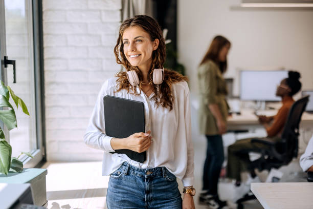 istock Young beautiful businesswoman enjoying a view while standing near window at modern office 1663283511
