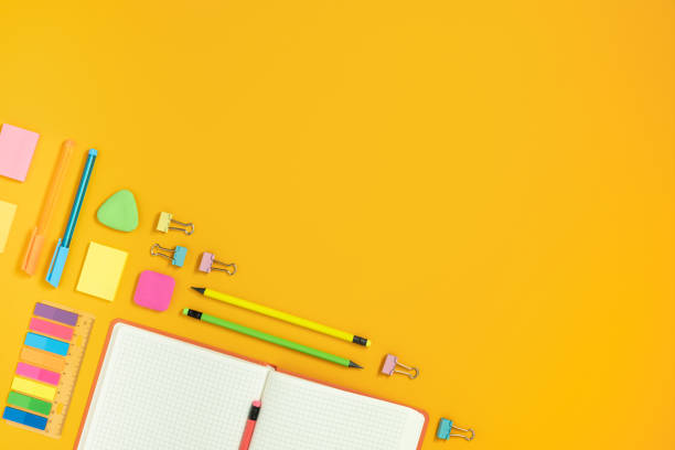 istock Frame of open note and colorful school and office stationery on yellow backdrop. 1663284055