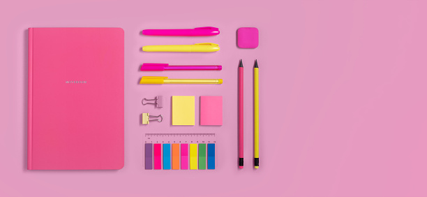 Yellow and pink school and office stationery on pastel pink background. Copyspace, flatlay.