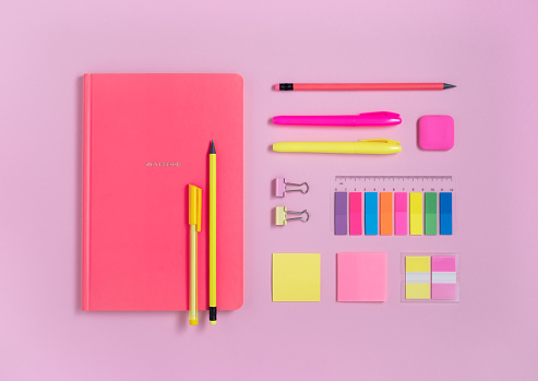 Yellow and pink school and office stationery on pastel pink background. Flatlay.