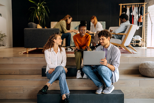 Colleagues using laptop while taking a break at modern office