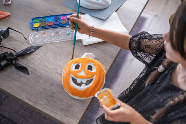 istock Little witch painting a mask for Halloween 1663296004
