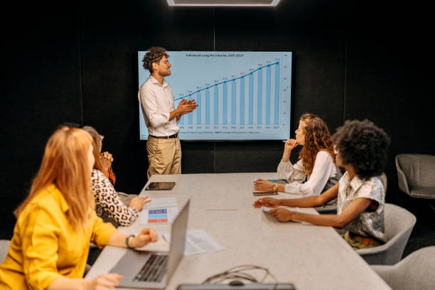 istock Young casually clothed businessman giving presentation to colleagues in conference room 1663297656