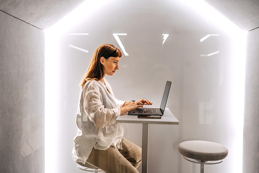 Young pregnant businesswoman using laptop in an office pod