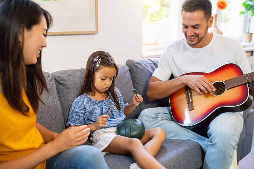 Multiracial Parents Teaching Their Daughter How To Play Tongue Drum multiracial-parents-teaching-their-daughter-how-to-play-tongue-drum