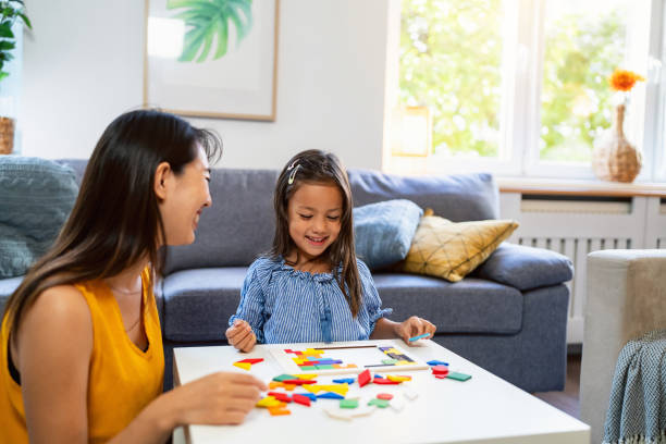 istock Playful mother and daughter Japanese ethnicity playing with multii-colored puzzles 1663330196