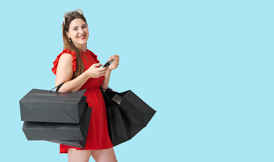 Happy woman holding shopping bags and a smartphone, Black Friday sale concept