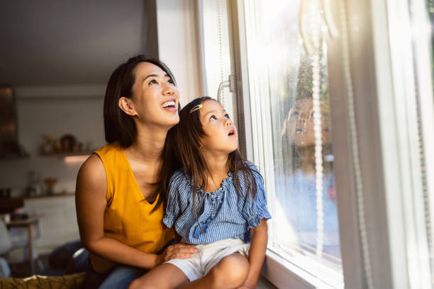 istock Mother and daughter Japanese ethnicity looking through window 1663340027