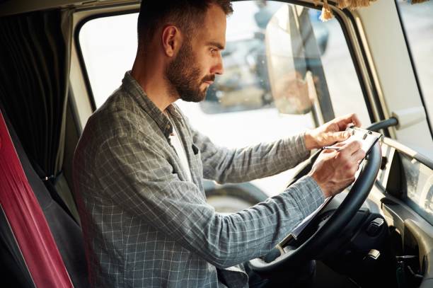 istock Writing in the document, sitting inside. Young truck driver in casual clothes 1663359120