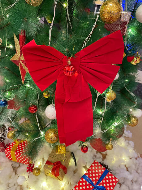 крупный план праздничной экспозиции торгового центра, искусственной, украшенной рождественской елки, окруженной снегом из ваты, бархатным - bow christmas red velvet стоковые фото и изображения