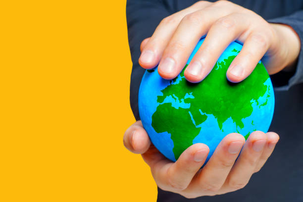 istock Man Holding Verdant Globe on Yellow Background 1663367304