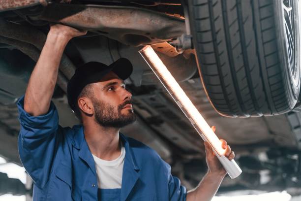 istock Under car, using lighting device. Auto mechanic working in garage. Repair service 1663379693