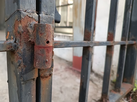 This image showcases an old black iron door hinge that has endured the test of time, bearing the marks of extensive rust and decay. The once-smooth surface of the hinge is now marred by the corrosive effects of rust, and the structural integrity has significantly deteriorated. The deep, rich black color has faded, replaced by the earthy tones of rust. This composition tells the story of aging and the relentless forces of nature, making it a compelling choice for various artistic and conceptual projects