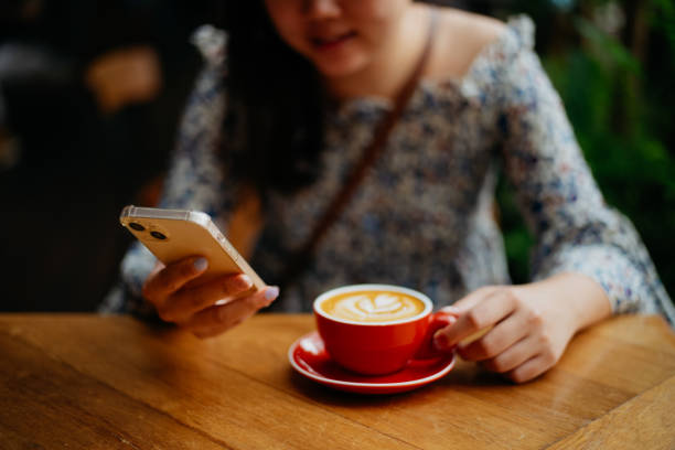 istock Asian woman using smartphone and having a coffee break in cafe 1663393167