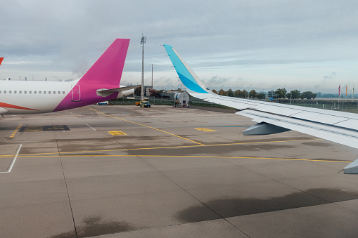 Airplanes parked on the tarmac at Dusseldorf airport. Focus on two airplane wings.