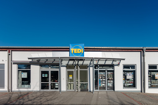 Amberg, Germany - November 13, 2022: Shop of the German non food trading chain TEDI in the town Amberg, Bavaria. Headquarter in Dortmund. More than 2950 shops in 15 countries. Wide assortment with decorating supplies, clothes, housewares, do-it-yourself items, stationery and so on. Sunny sunday afternoon with clear blue sky.
