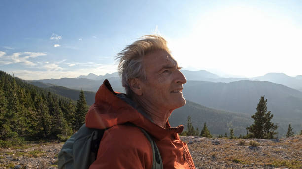reifer männlicher wanderer kommt auf berggipfel an - travel destinations mountain hiking profile stock-fotos und bilder