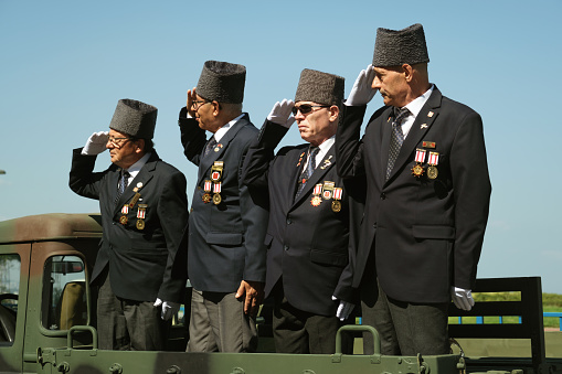 Izmir, Turkey - August 30, 2023: At Republic Square during the Victory Day celebrations, Four Turkish war veterans stand tall and salute from the bed of a military pickup, exemplifying national pride and respect