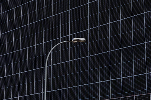 Close up detail of a vertical solar panel and a streetlight. Renewable energy concept.