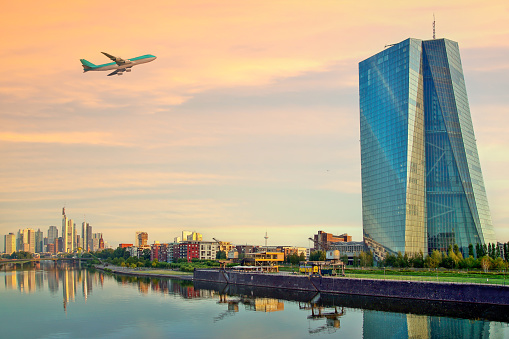 Airplane flying over the european city skyline and financial centre of Frankfurt am Main. Skyscraper buildings in Germany on sunset background. Business and finance concept