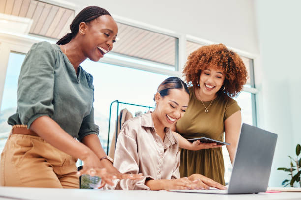istock Happy, employees and working together on tech in office with creative, stylist ideas for fashion and clothing on pc or tablet. Funny, colleagues or women in Colombia reading or typing on laptop 1663526387