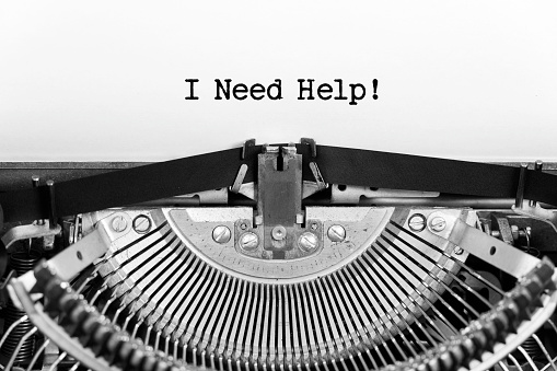 I need help phrase closeup being typing and centered on a sheet of paper on old vintage typewriter mechanical.