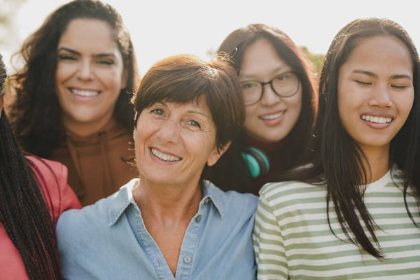 istock Group of multiracial women with different ages smiling in front of camera while hugging each other outdoor - Female community and multi generational concept 1663536909