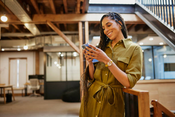 istock Cheerful businesswoman with cornrow braids using cellphone against handrails in office 1663562847