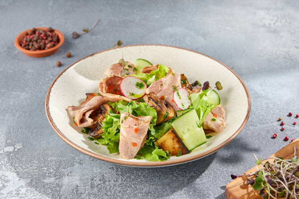 istock A minimalist composition featuring a salad with baked pork and vegetables on a ceramic plate, set against a grey concrete background. Ideal for showcasing healthy eating and gourmet cuisine 1663566351