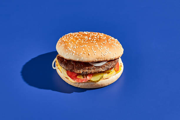 istock Beef burger blue background with hard shadow. American junk food minimal style. Hamburger trendy style.  Simple burger colour background. 1663570742