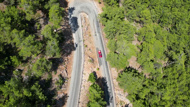 Vehicle in motion on the road in forest mountainous area asphalt curvy road shooting with drone