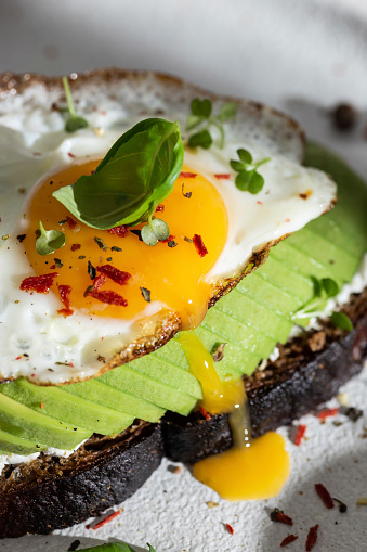 Toasted bread with avocado and fried egg for breakfast