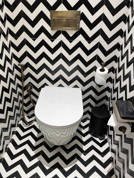 高級ホテルのバスルームの接写、白黒のジグザグパターンの壁と床のタイル、壁掛けプッシュボタンフラッシングセラミックトイレ、真ちゅう製のハンドシャワービデヘッドアタッチメント� - mobile phone smart phone toilet water ストックフォトと画像