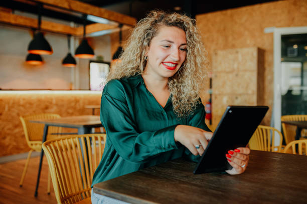 istock Businesswoman smiling at digital tablet on table in breakout space 1663604301