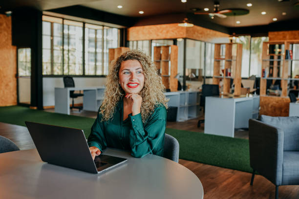 istock Confident businesswoman with laptop on table, looking sideways in modern coworking office 1663604872