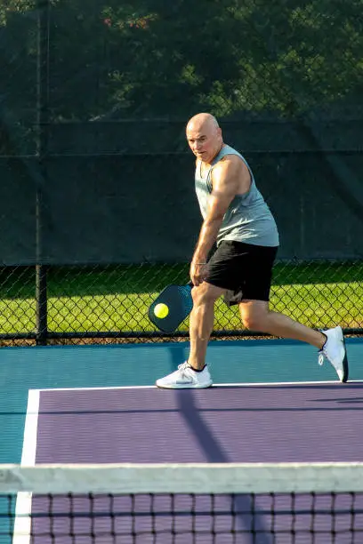 Photo of Male Pickleball Player Returns Serve with his Backhand