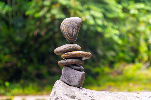 Female's hand stacking rocks by the river in Switzerland