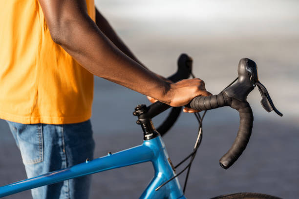 Closeup portrait of African man holding bicycle handlebars on urban street selective focus